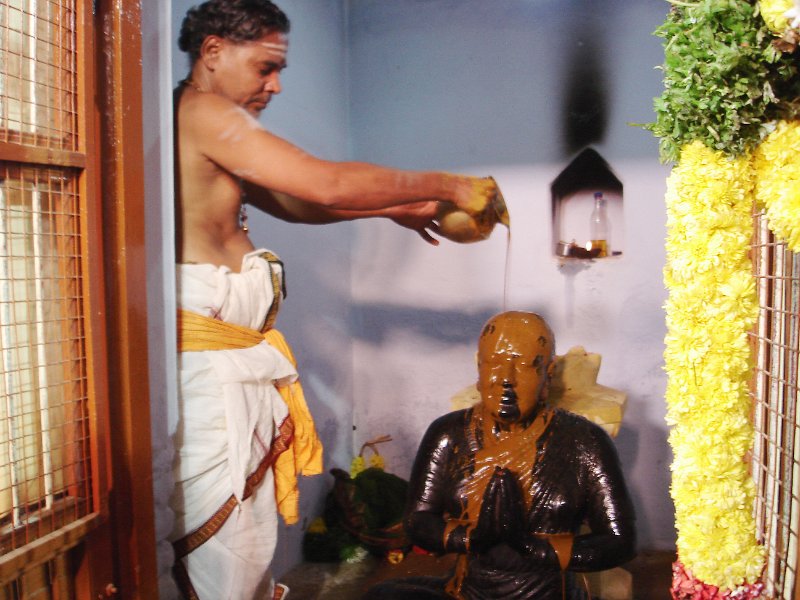 DSC03325.JPG - A priest performs abishekam at the image of Bangalore Nagaratnammal,  the woman who is said to have relocated Thiagaraja's samadhi and gave a new life to the aradhana tradition